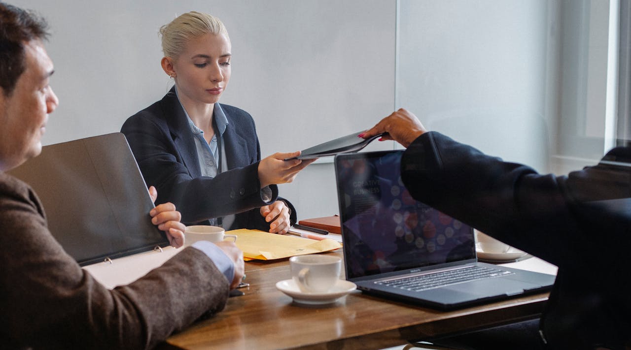 Diverse colleagues examining report of business project while using netbook at table in office